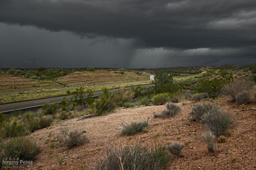 A supercell sports a lowering where the highway disappears into the hills. Meanwhile, trailing convection begins to merge into a bowing segment. View is to the northwest from Highway 93 a few miles south of I-40. 8:35 AM / 1535Z